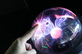 hand touching plasma globe