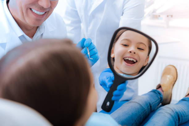 joyful cute girl looking into the mirror - dental light dental equipment hospital professional occupation imagens e fotografias de stock