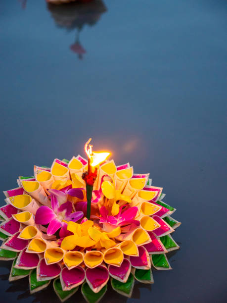 Lone krathong with burning incense at night Close-up detail of a colorful krathong ornately decorated with orchids and leaf foldings and a brightly burning incense stick, during the night of Loy Krathong, Thailand. Travel and holidays concept. krathong stock pictures, royalty-free photos & images