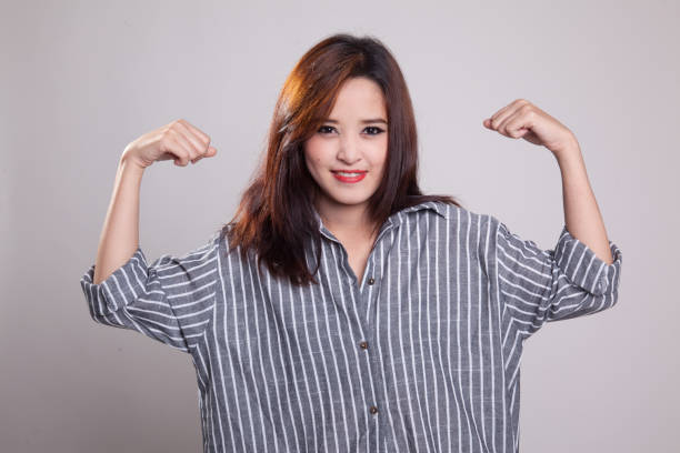 istock Beautiful young Asian woman flex bicep. 871850378