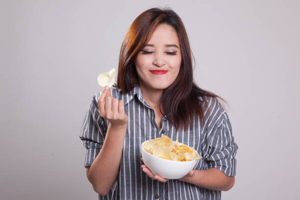 istock Young Asian woman eat potato chips. 871856606