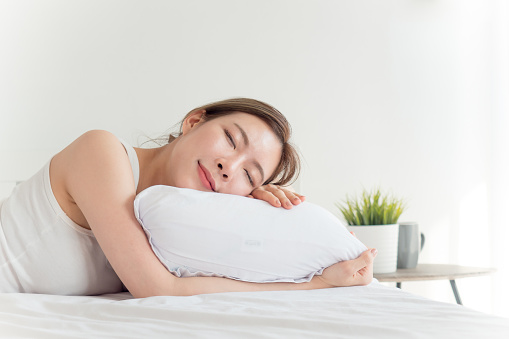 Young beautiful asian woman sleeping happy on white bed with happy feeling