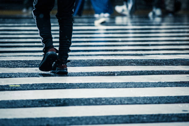 istock People across the crosswalk on a rainy day 871867538