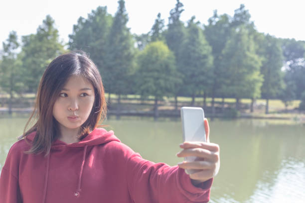 istock young woman taking a selfie at lakeside 871877754