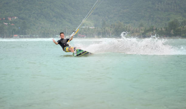 Happy handsome kite boarder surfing towards the camera with a candid smile.