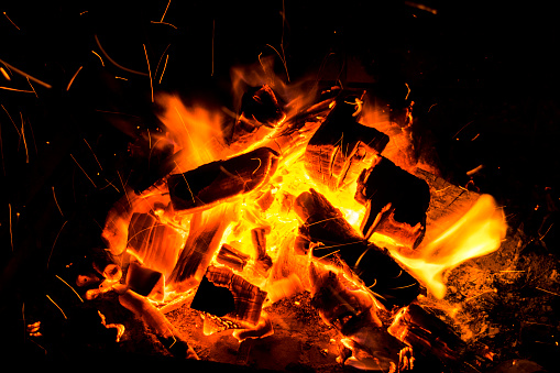 Abstract background with Burning firewood in the fireplace close up, BBQ fire, Sparking charcoal background. Spark of bonfire.