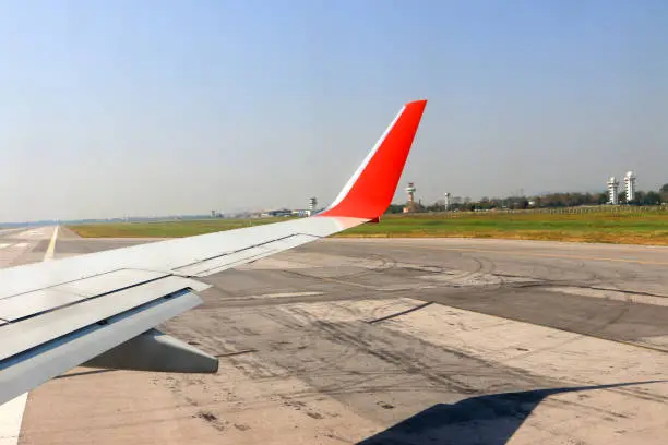 Photo of airplane wing on runway with red wingtip, airplane ready take off
