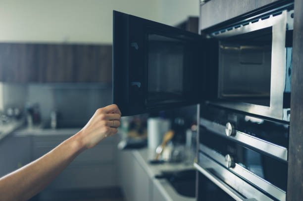 istock Young woman opening the microwave 871893576