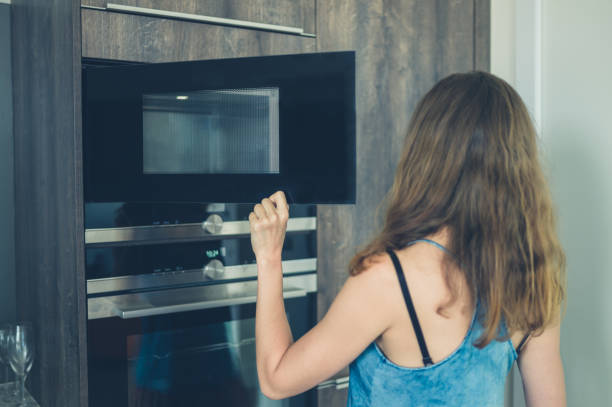 istock Young woman opening the microwave 871893678