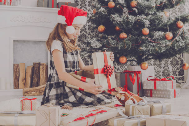 istock Beautiful girl in santa hat unwrapping christmas presents 871899430