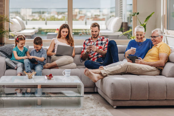 istock Happy extended family relaxing on the sofa and using wireless technology. 871900842