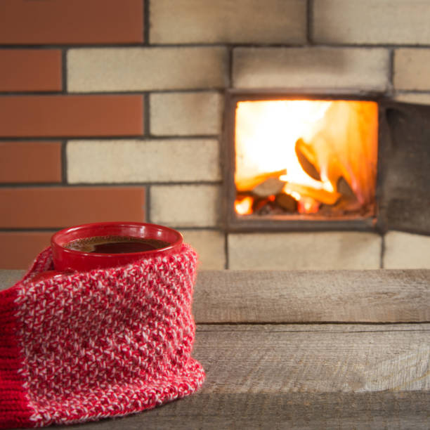 tazza di caffè rosso sul piano del tavolo vicino al camino. vacanze di natale. - brick red wool heat foto e immagini stock