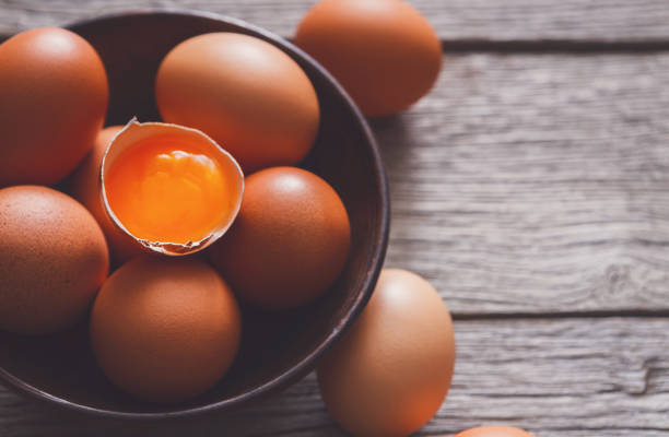 istock Fresh brown eggs in bowl on wood background 871909182