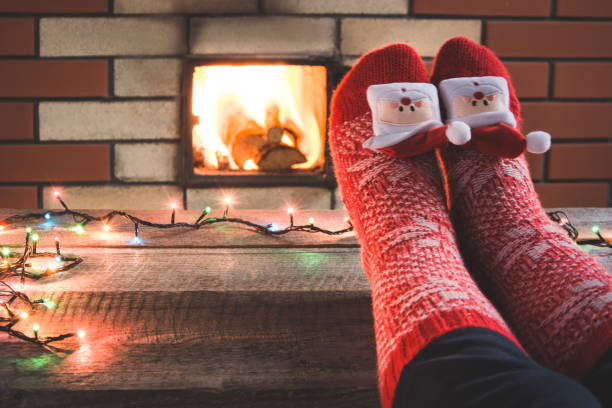 クリスマスの暖炉のそばに靴下ウール赤足。足の上にクローズ アップ。卓上のクリスマス商品が表示されます。 - brick red wool heat ストックフォトと画像
