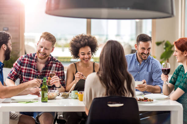 istock Group of happy friends having fun while eating at dining table. 871915684