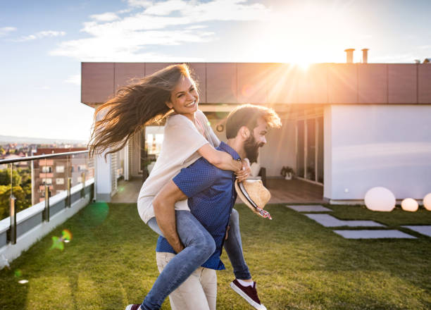 istock Joyful couple having fun while piggybacking on a penthouse balcony. 871916610