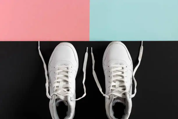 White sneakers on a black table and color backgrounds. Place for the advertizing text.