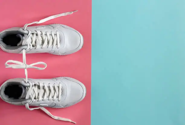 White sneakers on a pink background. The place for the text. Copy space