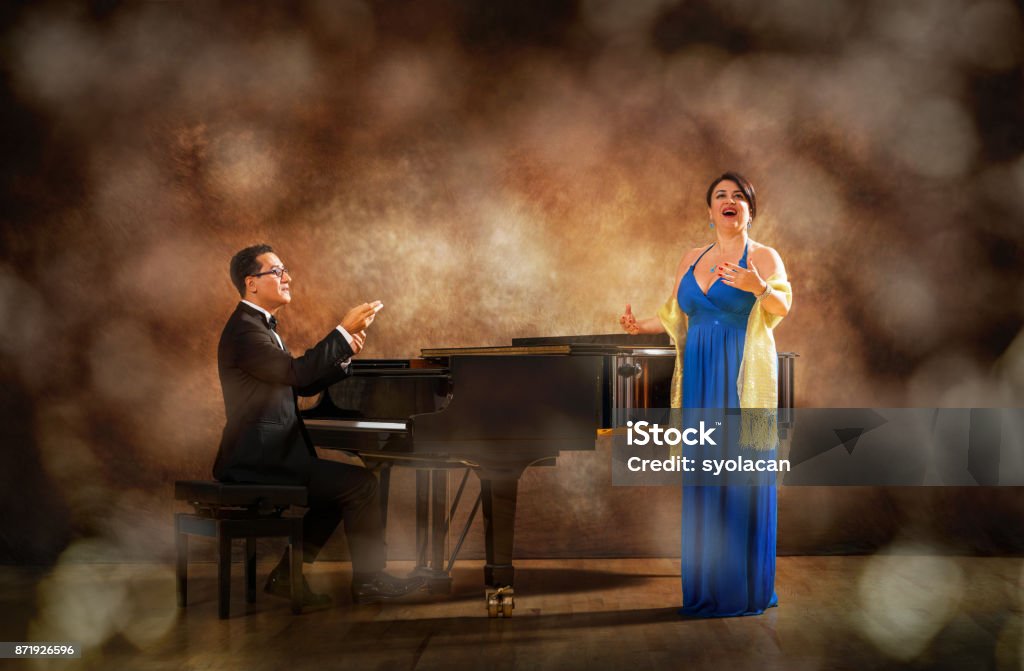 Pianist and singer during stage performance Professional pianist and woman singer on powerful stage performance. Singer Stock Photo