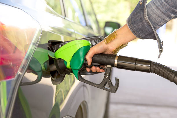 a woman's hand filling up gas - gas station gasoline refueling fuel pump imagens e fotografias de stock