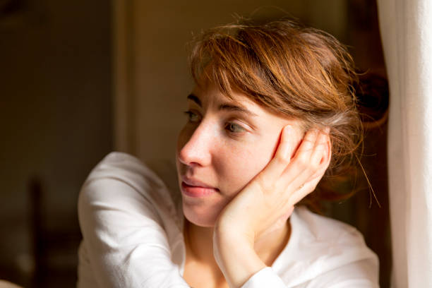 istock Beautiful woman sitting by window 871930328
