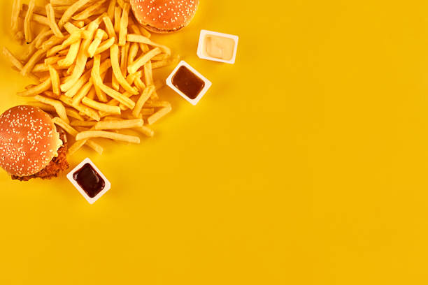istock Fast food concept with greasy fried restaurant take out as onion rings, burger, fried chicken and french fries as a symbol of diet temptation resulting in unhealthy nutrition 871949392