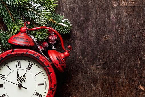 Christmas fir tree and alarm clock over old wooden texture background. Top view with copy space for your greetings