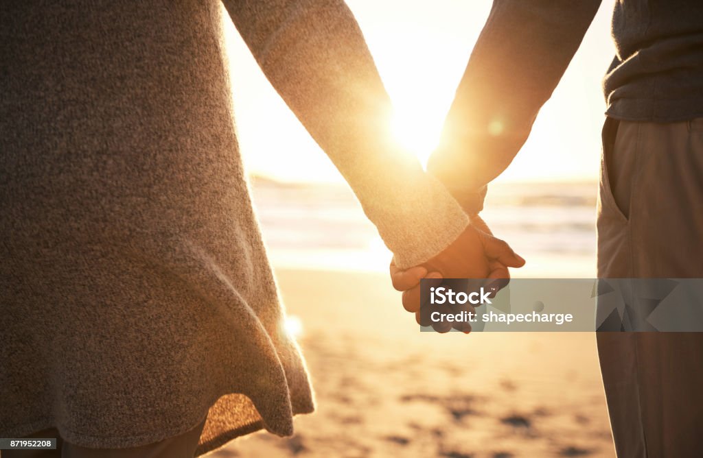 Never let go Rearview shot of an unrecognizable couple holding hands while at the beach Holding Hands Stock Photo