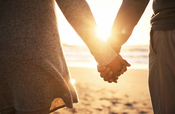 Never let go Rearview shot of an unrecognizable couple holding hands while at the beach couple holding hands stock pictures, royalty-free photos & images