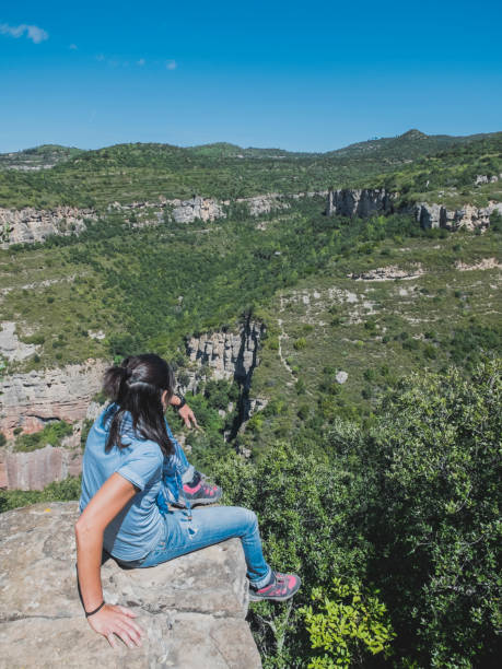 istock Young woman sitting on edge above the valley 871952252