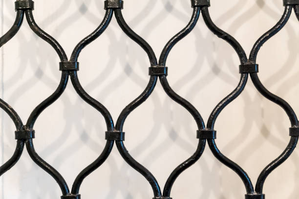 istock old black wrought-iron grating with shadow on the wall 871953116