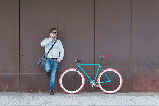 Stylish urban  businessman standing on the street with bicycle