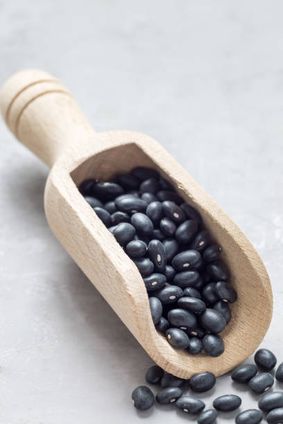 istock Black beans in a wooden scoop on gray concrete background, vertical, copy space 871971632