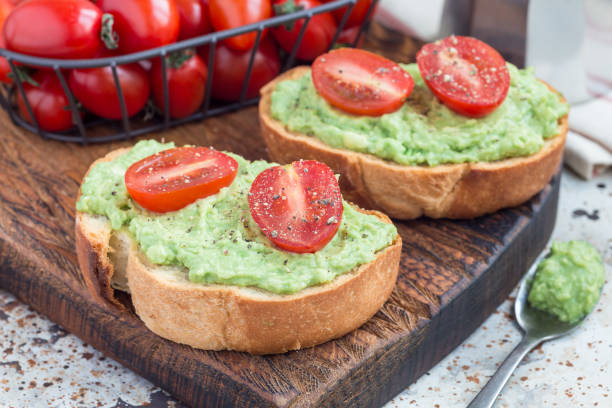 istock Open sandwich with mashed avocado and cherry tomatoes on toasted bread, sprinkled with black pepper, horizontal 871971682