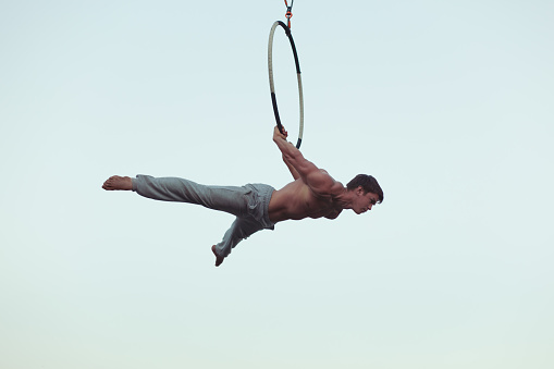 Man is an acrobat high in the sky, he shows the performance on the ring.