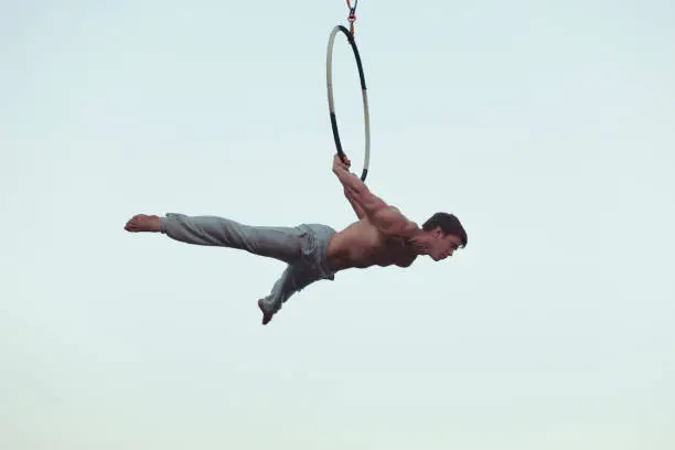 Man is an acrobat high in the sky, he shows the performance on the ring.