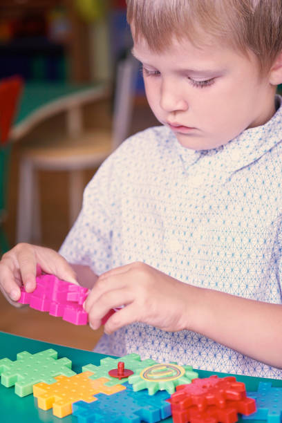 istock Little cute curly boy connects constructor's details in the children's room. 871973810