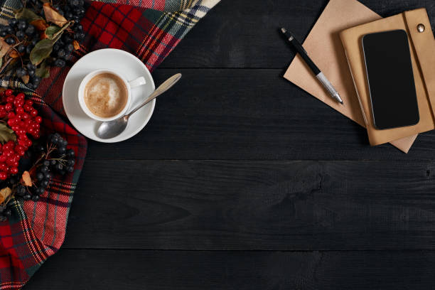 istock Smartphone with notebook and cup of coffee on wooden background. Cell phone with writing set with espresso 871977486