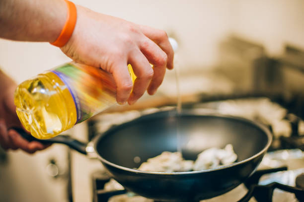 istock Chef cook pours oil into frying pan in the kitchen 871977584
