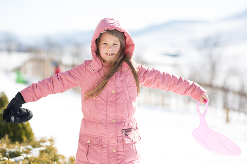Playful girl standing in the winter with her arms spread
