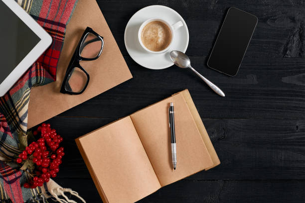 istock Notebook on wooden table with coffee cup, tablet and glasses beside in morning time 871983798