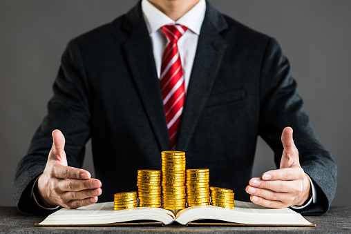businessman and gold coin placed on a book