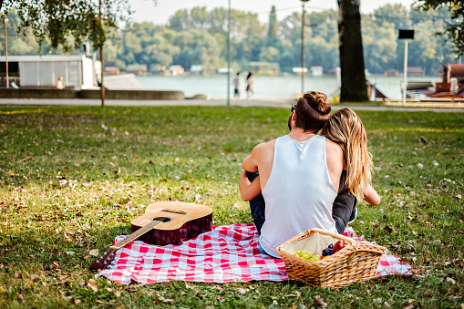 Couple hugging and looking at the river while on picnic