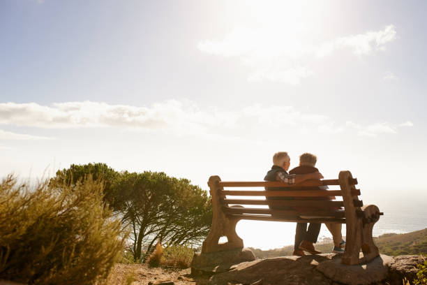 Stressless, sunny days Rearview shot of a senior couple sitting on a bench outdoors senior adult women park bench 70s stock pictures, royalty-free photos & images