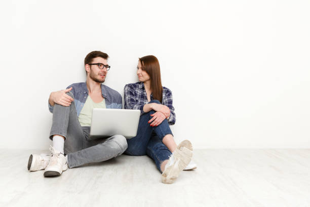 istock Casual couple discuss something sitting with laptop, studio shot 871988706