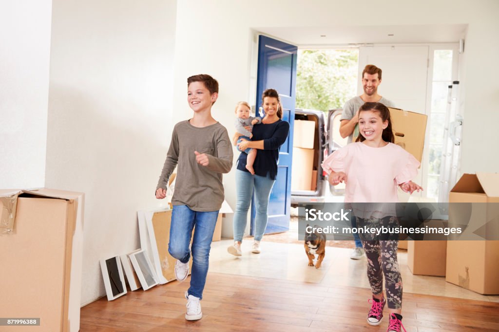 Family Carrying Boxes Into New Home On Moving Day Family Stock Photo