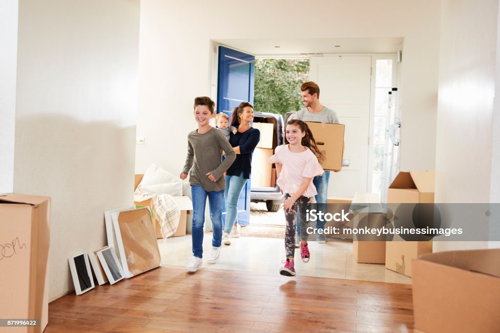 Family Carrying Boxes Into New Home On Moving Day Family Stock Photo