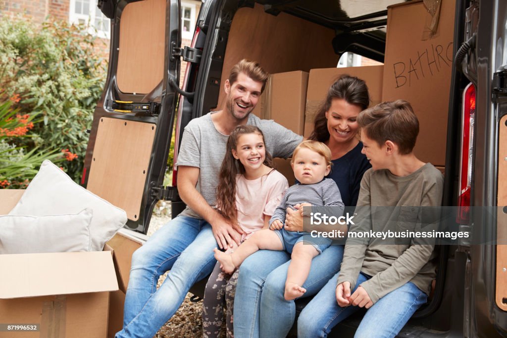 Family Sitting In Back Of Removal Truck On Moving Day 10-11 Years Stock Photo