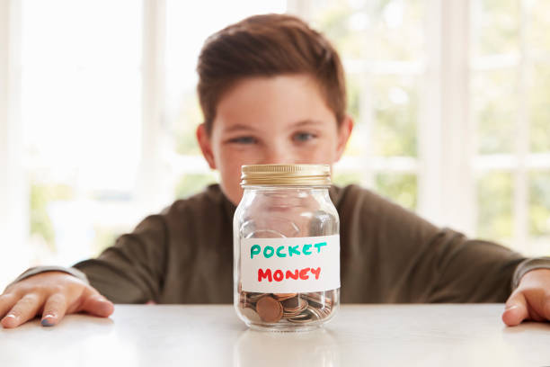 istock Boy Saving Pocket Money In Glass Jar At Home 871997846