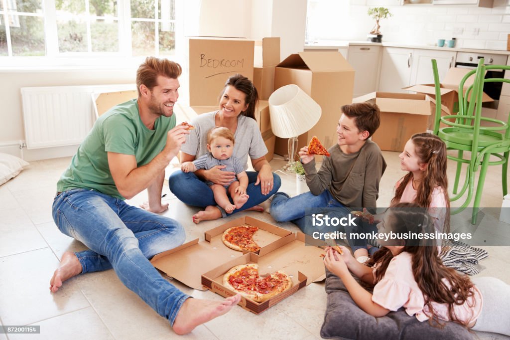 Family Celebrating Moving Into New Home With Pizza Eating Stock Photo